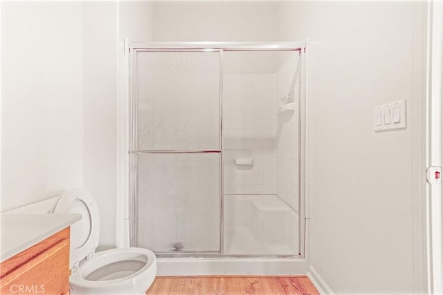 bathroom with vanity, toilet, wood-type flooring, and a shower with door