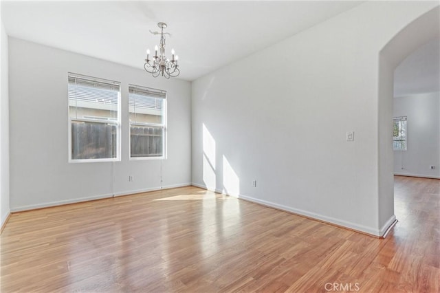 empty room featuring an inviting chandelier and light wood-type flooring