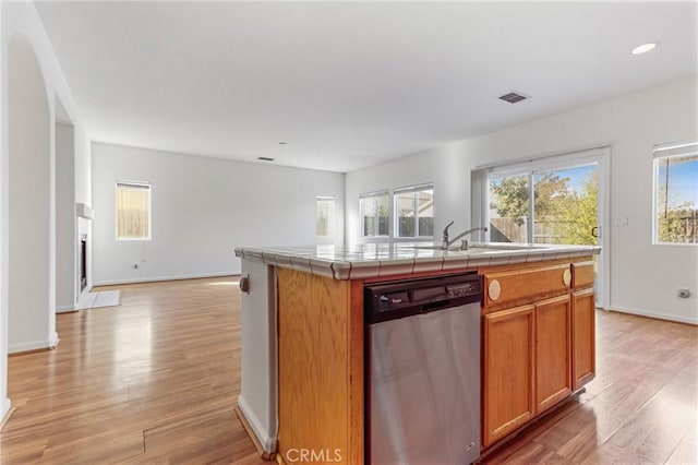 kitchen with stainless steel dishwasher, tile counters, light hardwood / wood-style floors, and a kitchen island