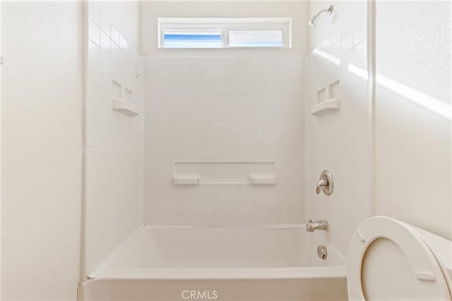 bathroom featuring tiled shower / bath combo and toilet