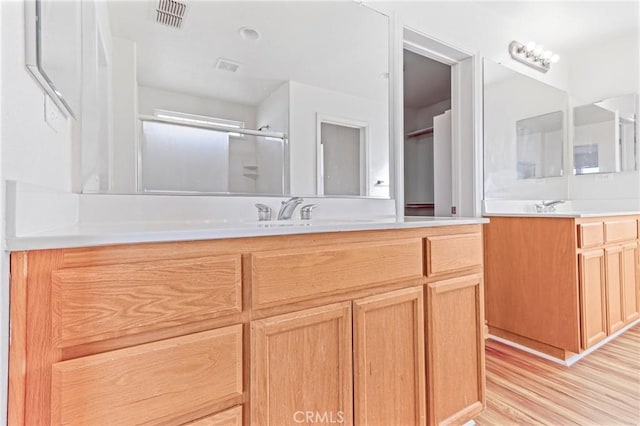 bathroom with hardwood / wood-style floors, vanity, and a shower with door