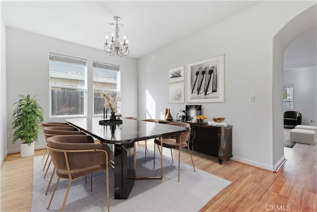 dining space with light hardwood / wood-style flooring and a notable chandelier