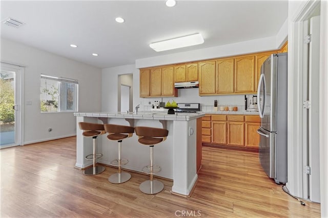 kitchen featuring stainless steel fridge, a center island, light hardwood / wood-style floors, and white stove