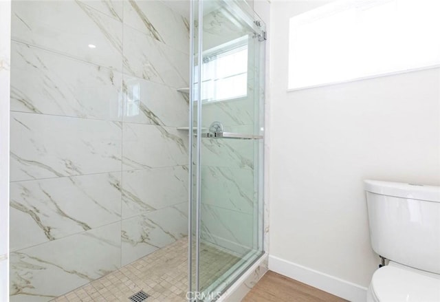 bathroom with toilet, a shower with door, and hardwood / wood-style floors