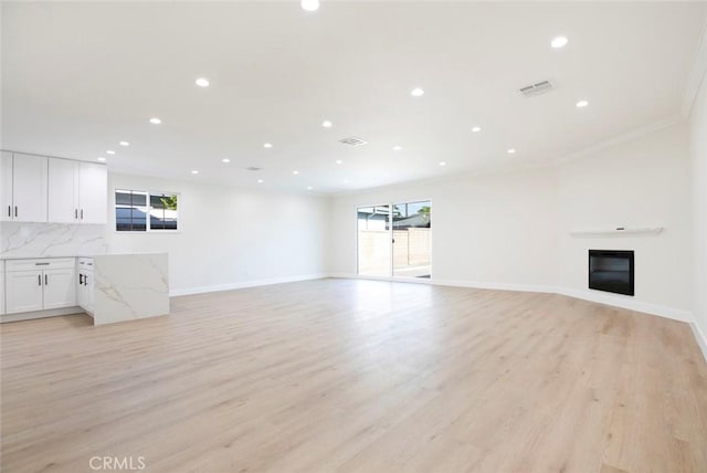 unfurnished living room featuring light hardwood / wood-style floors and crown molding