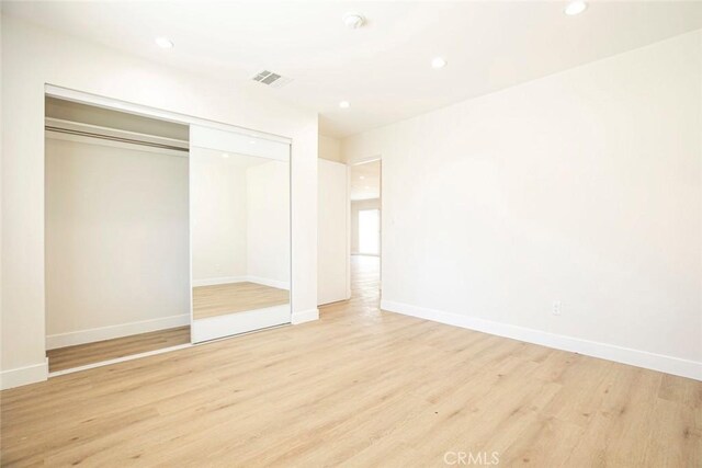 unfurnished bedroom with light hardwood / wood-style floors and a closet