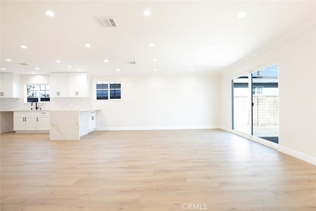 kitchen with white cabinetry, tasteful backsplash, light stone countertops, and light hardwood / wood-style flooring