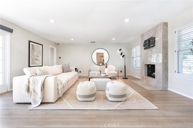 living room with a high end fireplace and light hardwood / wood-style flooring