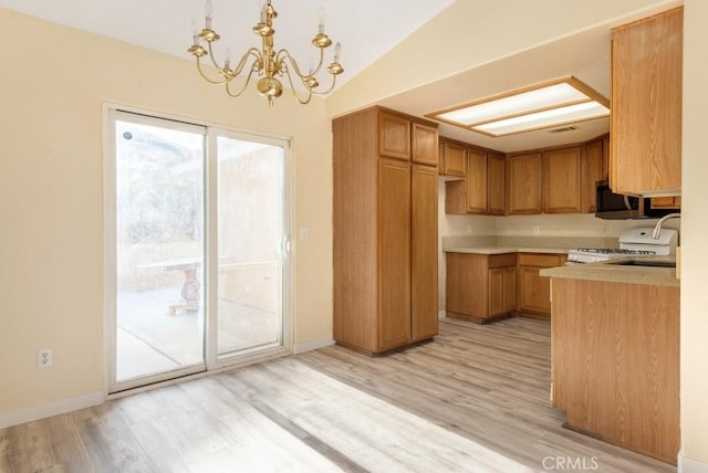 kitchen featuring vaulted ceiling, light hardwood / wood-style flooring, decorative light fixtures, and white stove