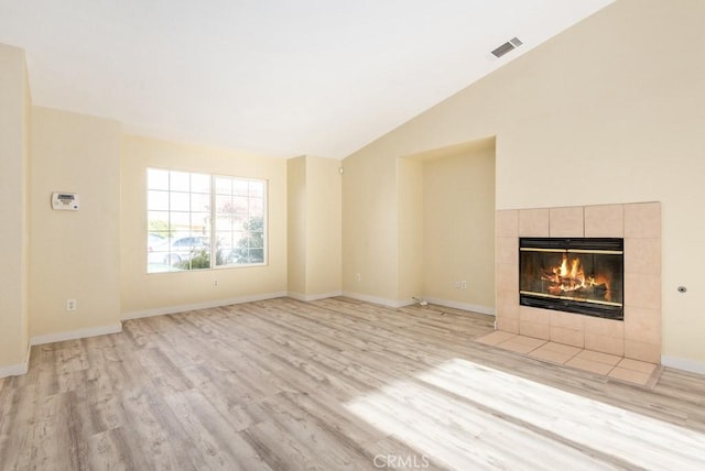 unfurnished living room featuring a fireplace, lofted ceiling, and light wood-type flooring