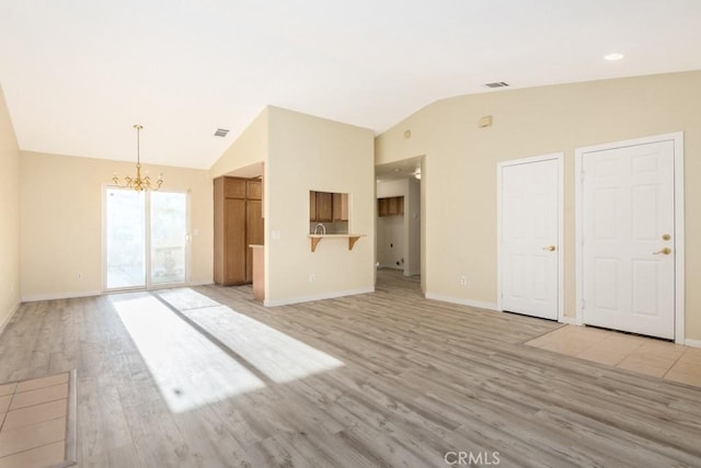 unfurnished living room featuring a notable chandelier, lofted ceiling, and light wood-type flooring