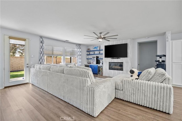 living room featuring a fireplace, light hardwood / wood-style floors, and ceiling fan