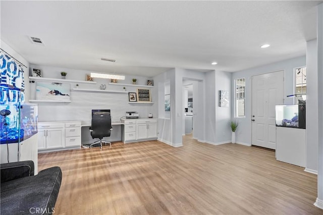 home office featuring washer / dryer, built in desk, and light hardwood / wood-style flooring