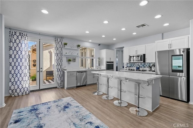 kitchen featuring white cabinetry, a kitchen island, light wood-type flooring, and appliances with stainless steel finishes