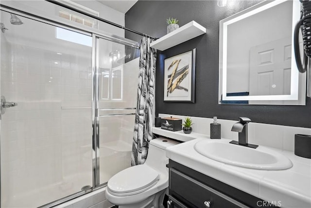 bathroom featuring a shower with door, vanity, and toilet