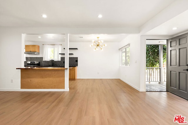 kitchen featuring tasteful backsplash, a wealth of natural light, stainless steel stove, and light hardwood / wood-style floors