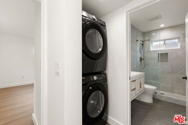 interior space featuring vanity, hardwood / wood-style flooring, a shower with door, and stacked washer and clothes dryer