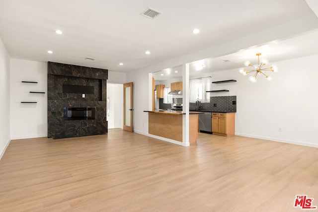 unfurnished living room featuring a chandelier, light hardwood / wood-style flooring, a fireplace, and sink