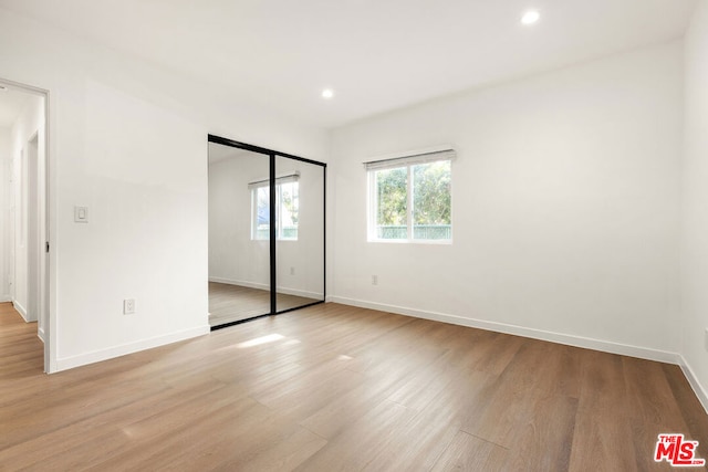 unfurnished bedroom with a closet and light hardwood / wood-style floors