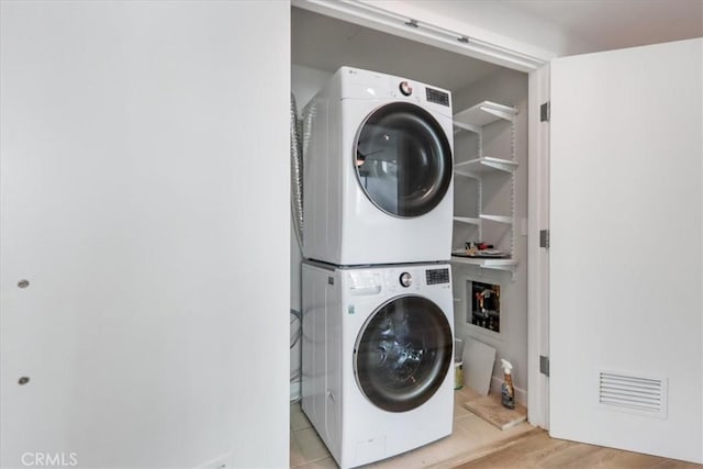 clothes washing area with stacked washer and dryer and light hardwood / wood-style flooring