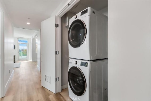 clothes washing area featuring stacked washer / drying machine and light hardwood / wood-style floors