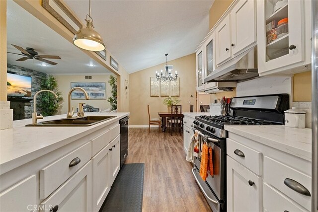 kitchen featuring light wood-type flooring, gas stove, sink, white cabinetry, and hanging light fixtures