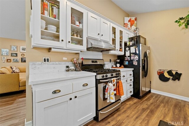 kitchen featuring white cabinets, hardwood / wood-style flooring, light stone countertops, and appliances with stainless steel finishes