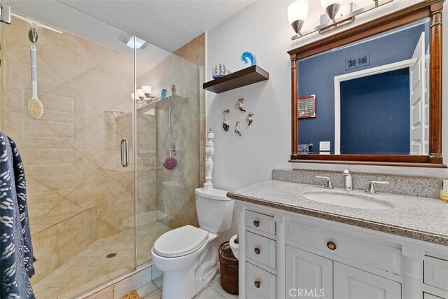 bathroom featuring a textured ceiling, vanity, a shower with door, tile patterned flooring, and toilet