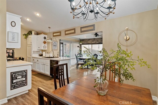 dining space featuring ceiling fan with notable chandelier, sink, and light hardwood / wood-style flooring