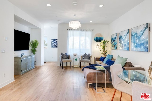 living room with light hardwood / wood-style floors and an inviting chandelier