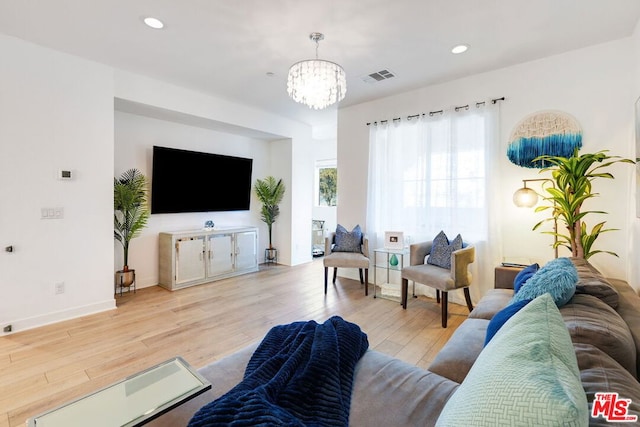 living room with light wood-type flooring and an inviting chandelier