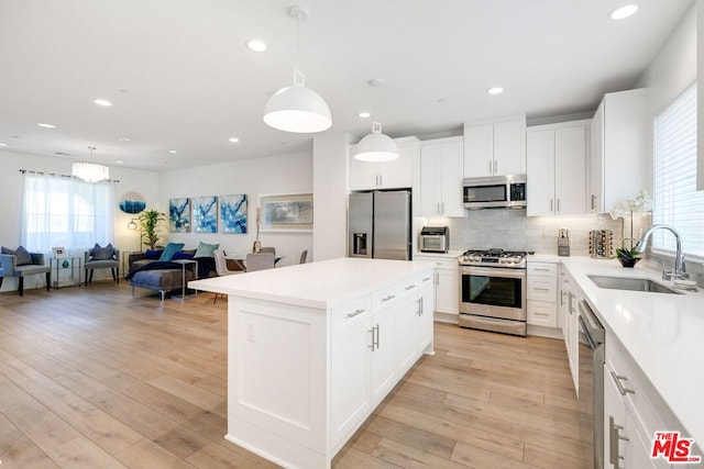 kitchen with pendant lighting, white cabinetry, sink, and appliances with stainless steel finishes