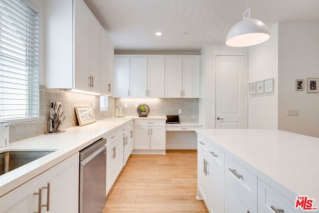 kitchen with stainless steel dishwasher, backsplash, decorative light fixtures, white cabinets, and light wood-type flooring