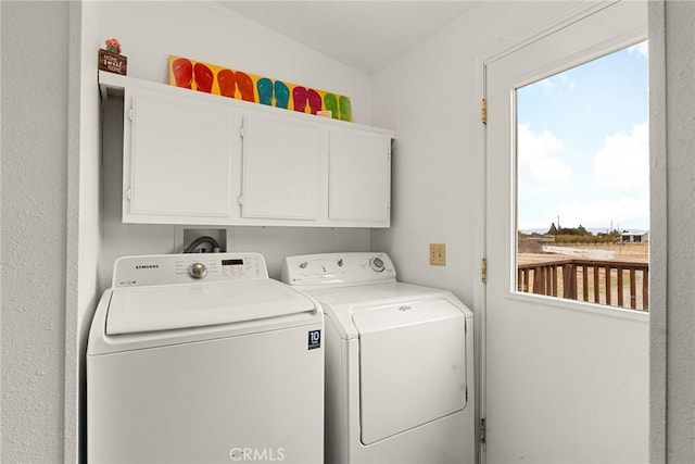 clothes washing area featuring cabinets and washing machine and dryer