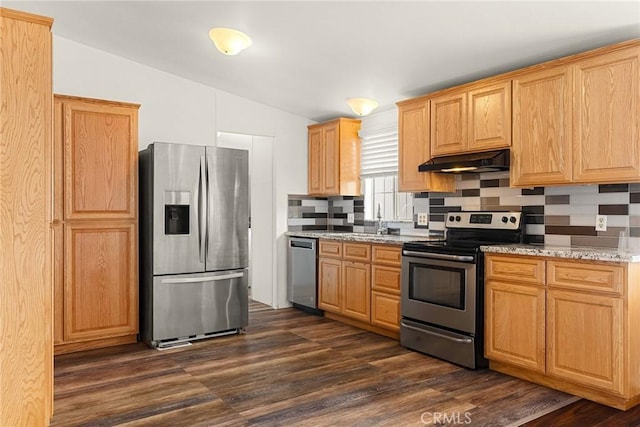 kitchen featuring light stone countertops, dark wood-type flooring, appliances with stainless steel finishes, and vaulted ceiling