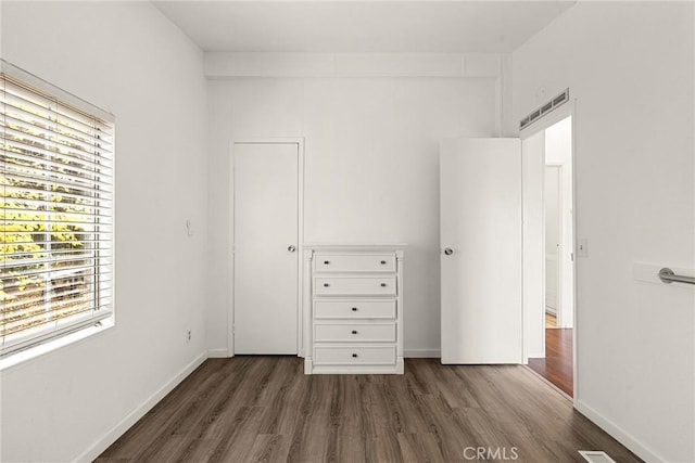 unfurnished bedroom featuring multiple windows and dark wood-type flooring