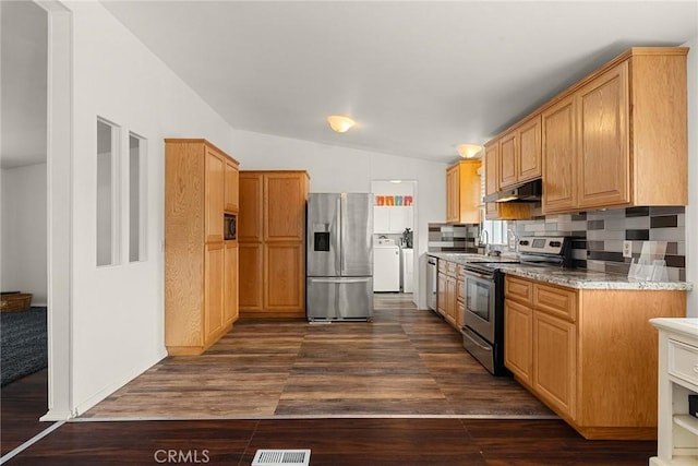 kitchen with dark hardwood / wood-style flooring, light stone counters, stainless steel appliances, washing machine and dryer, and lofted ceiling