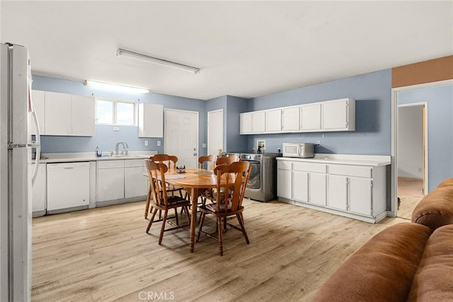 dining space with light hardwood / wood-style floors, washer / dryer, and sink