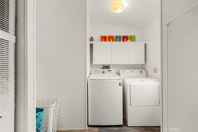 laundry room with hardwood / wood-style floors, cabinets, and washing machine and dryer