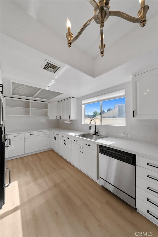 kitchen featuring white cabinetry, sink, stainless steel dishwasher, light hardwood / wood-style floors, and decorative backsplash