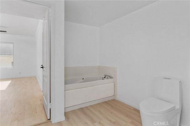 bathroom with hardwood / wood-style floors, a bathtub, and toilet