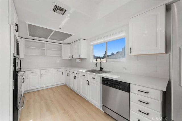 kitchen featuring sink, light wood-type flooring, tasteful backsplash, white cabinetry, and stainless steel appliances