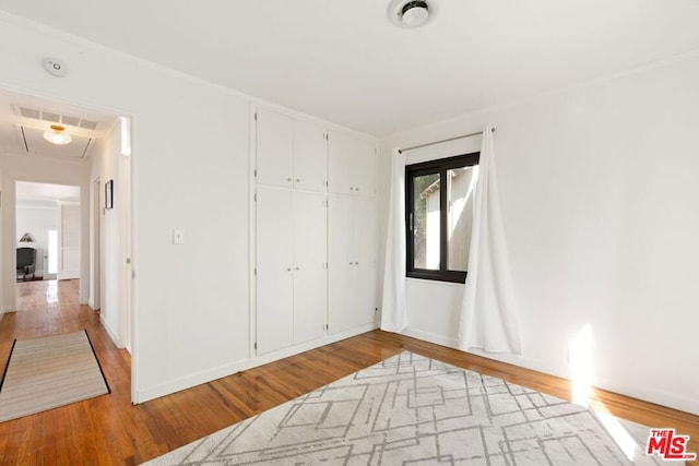 unfurnished bedroom featuring light wood-type flooring, a closet, and ornamental molding