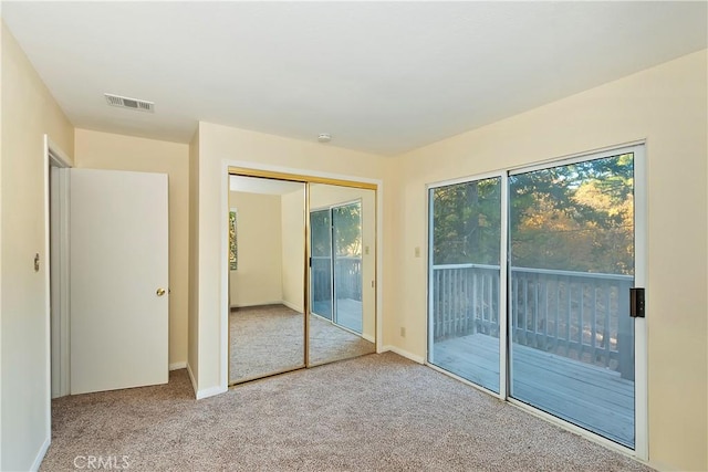 unfurnished bedroom with access to exterior, light colored carpet, and a closet