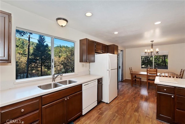 kitchen with white appliances, sink, hardwood / wood-style flooring, a chandelier, and hanging light fixtures