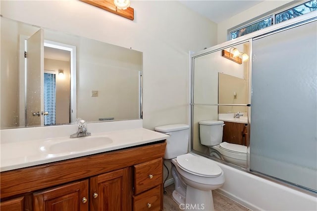 full bathroom featuring combined bath / shower with glass door, vanity, and toilet