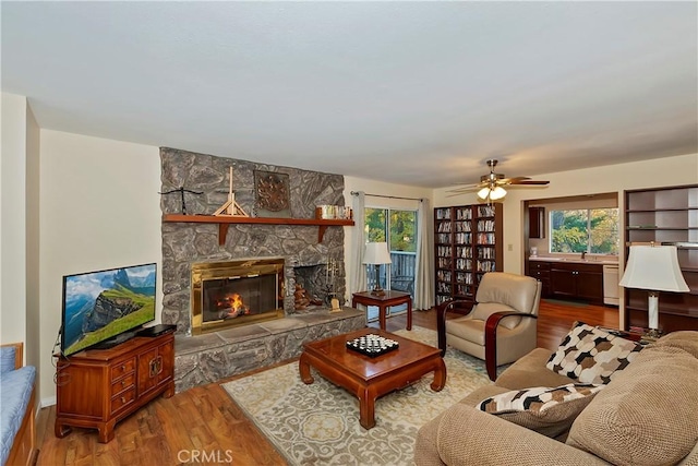 living room featuring hardwood / wood-style floors, ceiling fan, sink, and a fireplace