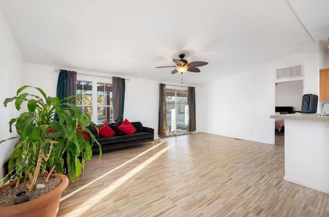 living room with ceiling fan, a wealth of natural light, and light hardwood / wood-style floors