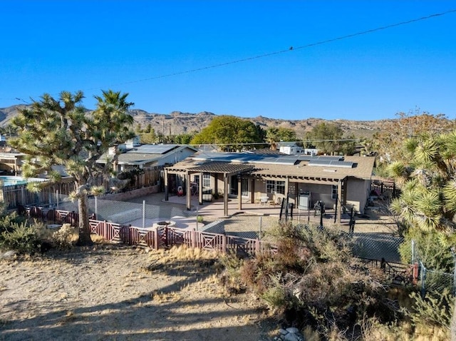 rear view of house with a mountain view, a patio area, solar panels, and a pergola