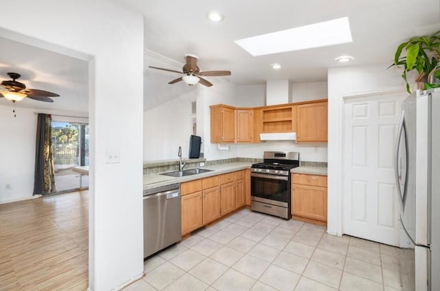 kitchen featuring ceiling fan, sink, appliances with stainless steel finishes, and vaulted ceiling with skylight